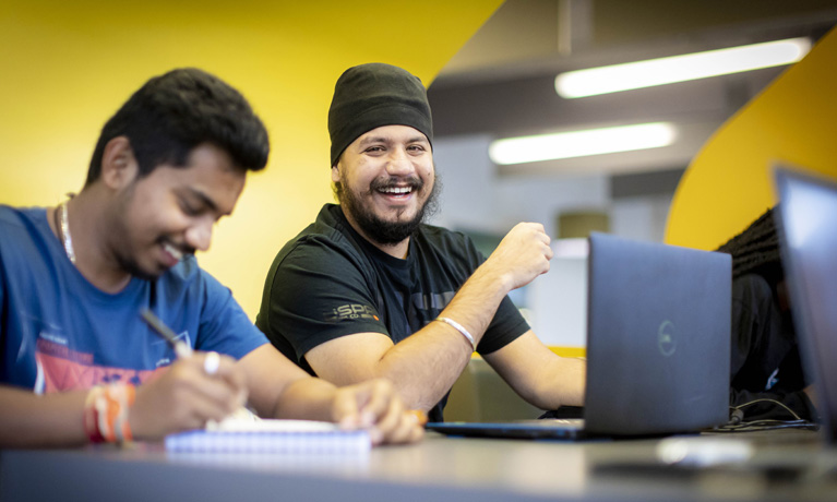 Students smiling while using laptops.