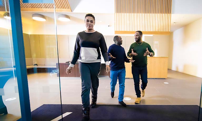 Three students walking out of the CU London Greenwich building